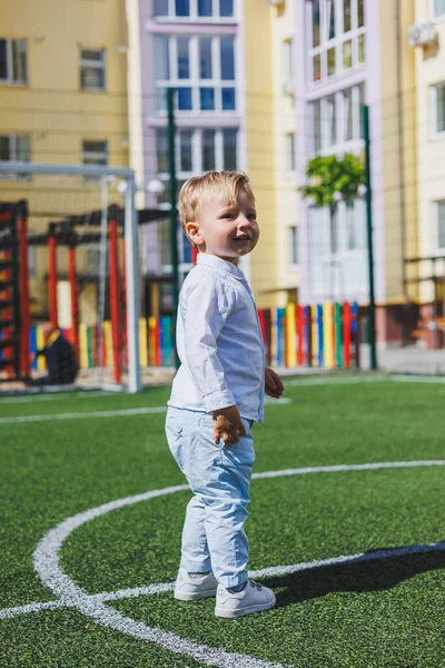 A little boy 2 years old in a shirt and trousers runs and laughs. A child on a sunny day rejoices and smiles.