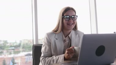 Aydınlık ofiste çalışan genç bir kadın. Dizüstü bilgisayarında internette sörf yapan uzun saçlı çekici bir kadın..