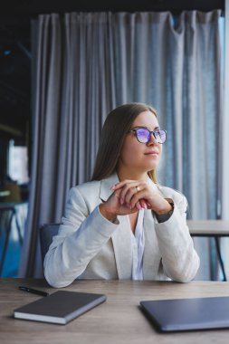 Successful young female manager in an elegant casual jacket and optical glasses, sits in the office at the workplace, an experienced woman with a modern laptop, working in the office