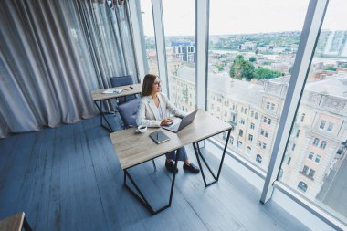 Gündelik giyim ve gözlük takan yönetici, modern çalışma alanındaki masada oturan yeni proje üzerinde çalışırken netbook 'ta daktilo ediyor.