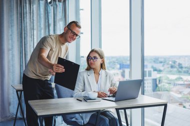 A young woman at a laptop in glasses sits at a table, having a corporate business meeting with colleagues in a modern office. business career concept. Free space, selective focus