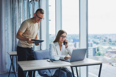 A young woman at a laptop in glasses sits at a table, having a corporate business meeting with colleagues in a modern office. business career concept. Free space, selective focus