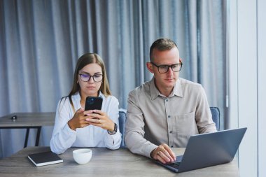 Ofiste dizüstü bilgisayar kullanan neşeli iş adamları. Modern bir çalışma alanında birlikte çalışırken gülümseyen genç girişimciler. Masada birlikte oturan iki genç iş adamı..