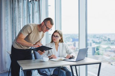 A young woman at a laptop in glasses sits at a table, having a corporate business meeting with colleagues in a modern office. business career concept. Free space, selective focus