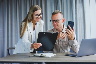 Erkek ve kadın meslektaşları dizüstü bilgisayarda ofiste çalışma süresi boyunca online formatta proje bilgileri üzerinde beyin fırtınası, genç başarılı ortaklar haber okuma ve netbook üzerinde fikir paylaşımı