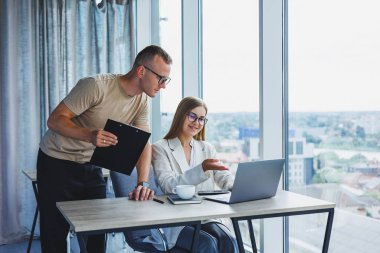 A young woman at a laptop in glasses sits at a table, having a corporate business meeting with colleagues in a modern office. business career concept. Free space, selective focus