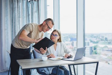 A young woman at a laptop in glasses sits at a table, having a corporate business meeting with colleagues in a modern office. business career concept. Free space, selective focus