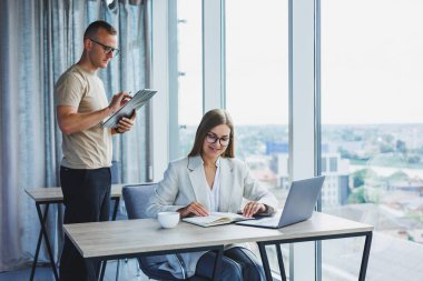 A young woman at a laptop in glasses sits at a table, having a corporate business meeting with colleagues in a modern office. business career concept. Free space, selective focus