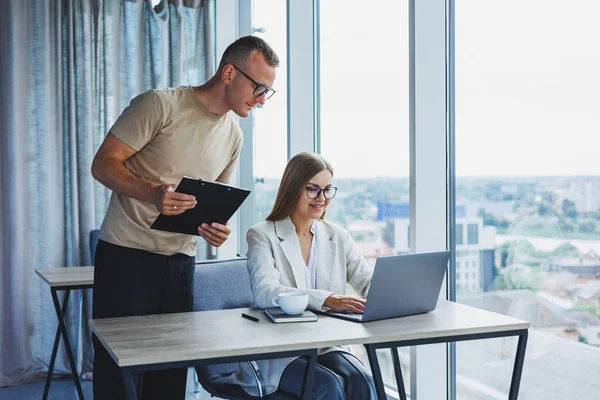 A young woman at a laptop in glasses sits at a table, having a corporate business meeting with colleagues in a modern office. business career concept. Free space, selective focus