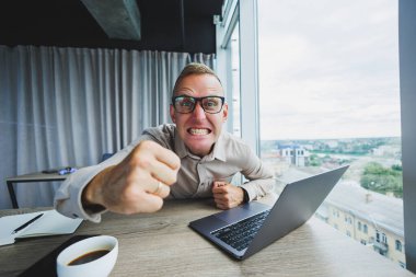 İş yerinde kameraya bakan duygusal bir adam, gözlüklü bir adam, bilgisayarlı bir masada oturuyor, bir öğrenci bir ofis kafesinde yeni fikirler için ilham arıyor.