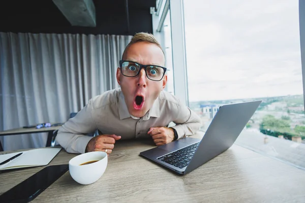 İş yerinde kameraya bakan duygusal bir adam, gözlüklü bir adam, bilgisayarlı bir masada oturuyor, bir öğrenci bir ofis kafesinde yeni fikirler için ilham arıyor.