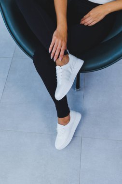 Women's legs close-up in white leather sneakers made from natural leather.Collection of women's summer shoes