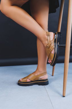 Women's brown leather sandals on the legs close-up. Collection of summer women's shoes