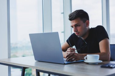 Happy man in optical glasses for vision correction looking for funny information in social networks using wireless connection on netbook, technology concept
