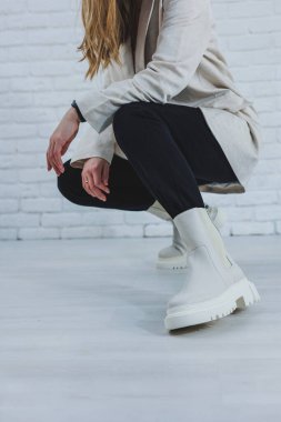 Women's legs close-up in white autumn boots. Women's boots made of genuine leather