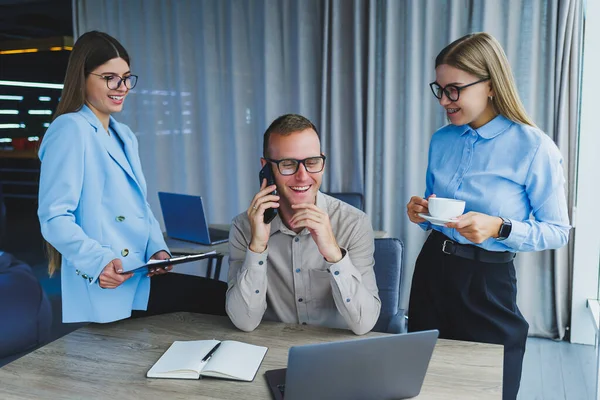 Successful young business people laughing while collaborating on a new project in the office. Group of diverse business people using laptop while working together in modern workspace.