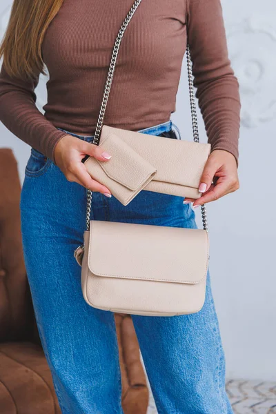 Stylish look. Close-up of beige handbag in hands. Fashionable girl. Close-up photo of a girl with a handbag in her hands.