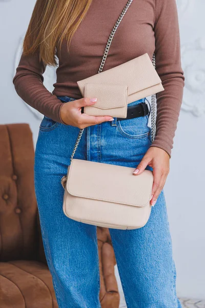 Stylish look. Close-up of beige handbag in hands. Fashionable girl. Close-up photo of a girl with a handbag in her hands.