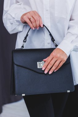 Black classic leather bag in a girl's hand. Woman with luxury bag.