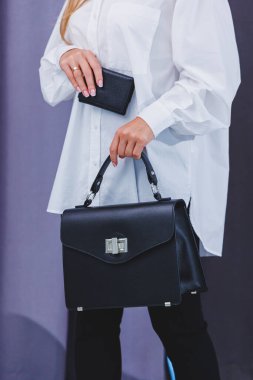Black classic leather bag in a girl's hand. Woman with luxury bag.