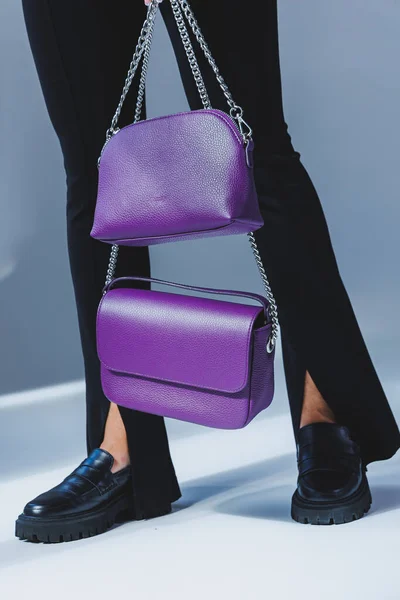 A purple leather bag in a girl\'s hand. Woman with luxury bag.