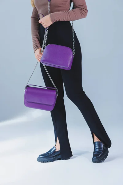 A purple leather bag in a girl\'s hand. Woman with luxury bag.