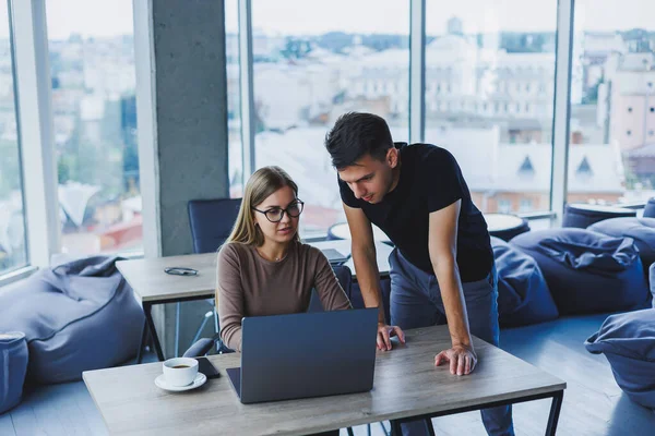 İki meslektaş bir dizüstü bilgisayarda çalışmayı tartışıyor. Ofiste iki meslektaş arasında dostça ilişkiler. Ofiste iş akışı