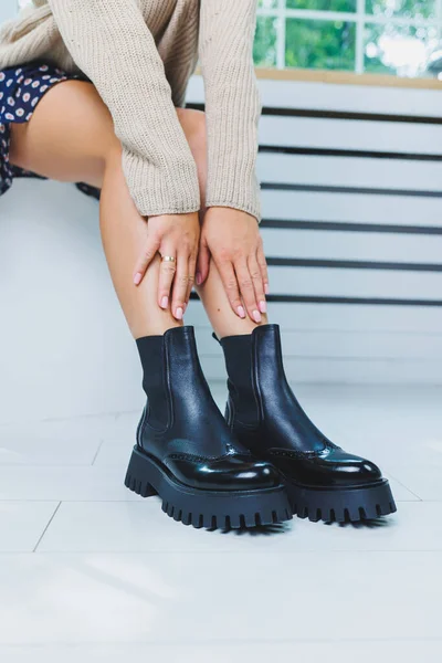 Close-up of black women\'s boots. Black boots made of genuine leather. Close-up photo of a woman\'s legs in warm boots