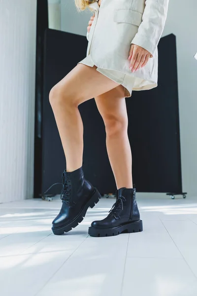 Close-up of black women\'s boots. Black boots made of genuine leather. Close-up photo of a woman\'s legs in warm boots