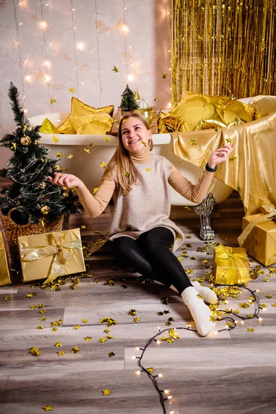 Happy woman in New Year\'s room. New Year\'s decoration of the room in golden color. The concept of the holiday and festive design. Home decor for the New Year.