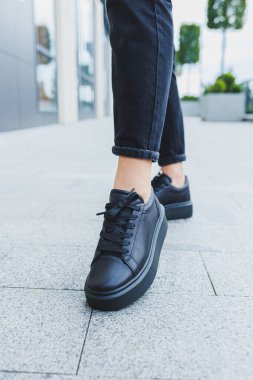 Siyah kot ve siyah dantelli ayakkabılı kadın bacakları. Siyah deri ayakkabılar. Yakın plan.