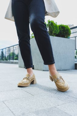 Siyah kot ve yüksek topuklu bej renkli kadın bacakları. Bej rengi deri ayakkabılar. Yakın plan.