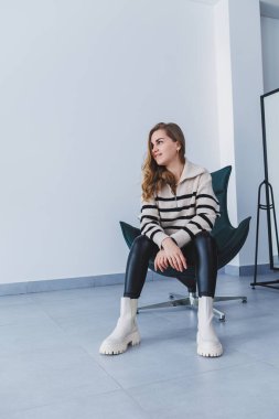 Güzel elbiseli ve beyaz deri çizmeli güzel bir kadın. Sonbahar kadın imajı.