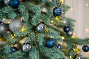 Mavi ve gümüş oyuncaklı Noel ağacı. Şenlikli Noel ağacı çelenklerle süslenmiş. Yeni yılın sembolü.