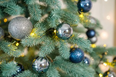 Mavi ve gümüş oyuncaklı Noel ağacı. Şenlikli Noel ağacı çelenklerle süslenmiş. Yeni yılın sembolü.