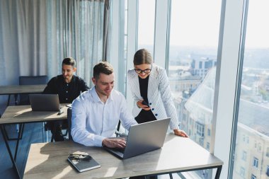 Modern ofis. Genç iş adamları resmi olarak proje detaylarını tartışıyor ve modern yönetim kurulunda iş birliği yaparken dizüstü bilgisayarın ekranına bakıyor..