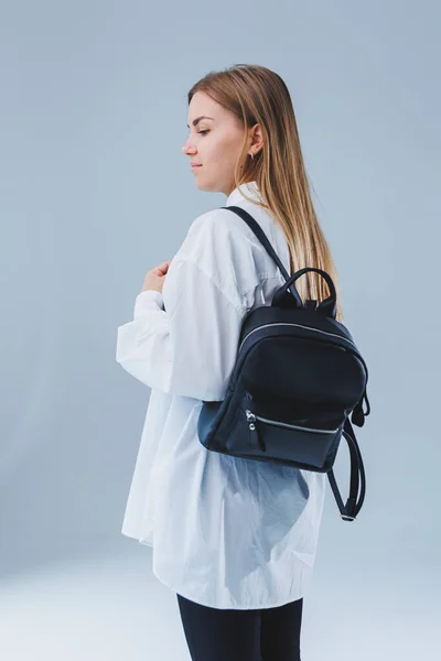 Black leather backpack in a woman's hand. A man with a luxurious leather backpack. Women's bags