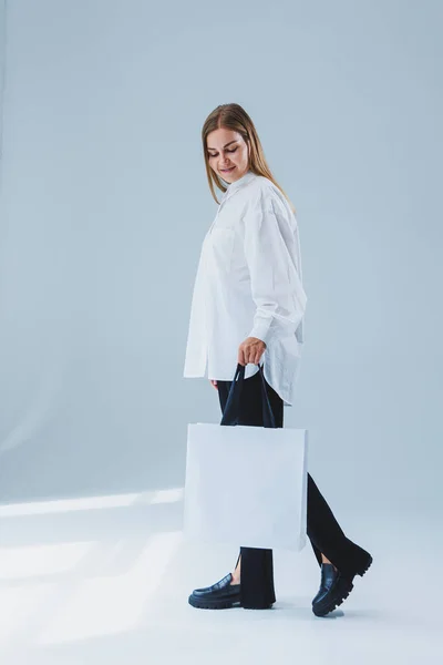 Stylish woman on a white background with a shopping bag. Eco bag for shopping.