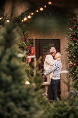 Genç ve mutlu bir çift Noel için dekore edilmiş evin yanında duruyor. Noel, Yeni Yıl, Kış tatili.