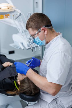 Bir dişçi bir hastanın dişlerini tedavi eder. Modern ilerici dişçilik. Araçları olan diş hekimi ofisi.