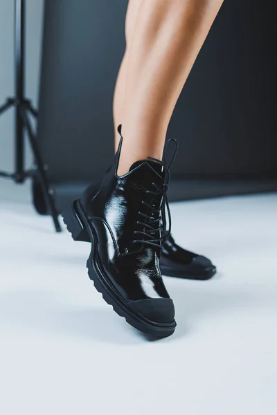 流行の女性が店に立って秋の靴を測定します スタイリッシュなファッションレザーブラックレースアップブーツで女性の足のクローズアップ 新しい季節のコレクションの女性の靴 — ストック写真