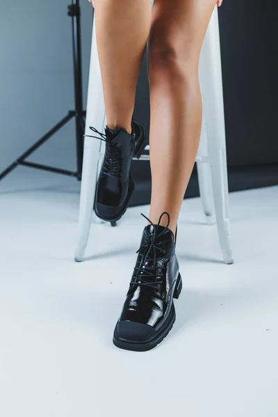 A fashionable woman stands in a store and measures autumn shoes. Close-up of female legs in stylish fashion leather black lace-up boots. New seasonal collection of women\'s shoes.
