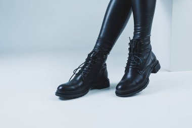 Deri çizmeli kadın bacakları. Moda kızı mağazada durur ve ayakkabıları ölçer..