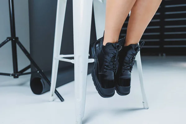 A fashionable woman stands in a store and measures autumn shoes. Close-up of female legs in stylish fashion leather black lace-up boots. New seasonal collection of women's shoes.