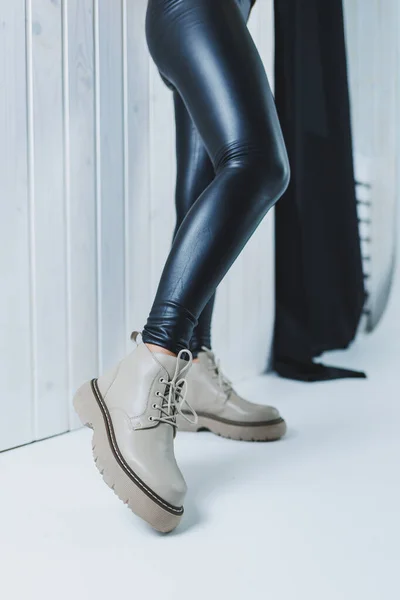 Female legs in leather beige autumn boots. A girl stands in a store and measures shoes.