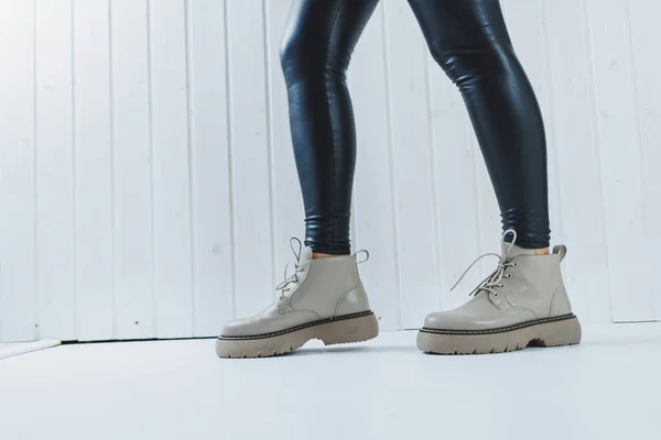 Female legs in leather beige autumn boots. A girl stands in a store and measures shoes.