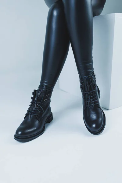 Female legs in leather black autumn boots. A fashion girl stands in a store and measures shoes.