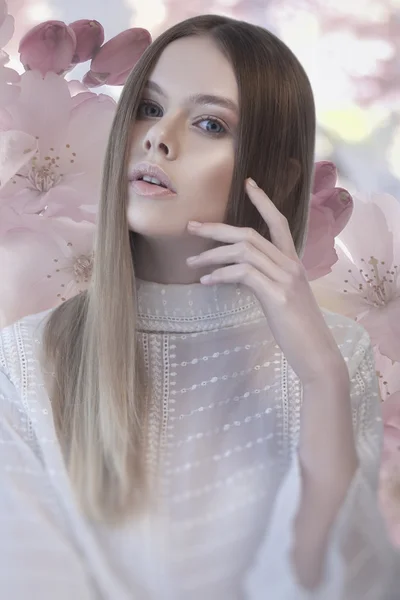 Pretty woman with hand near her face and flower background — Stock Photo, Image