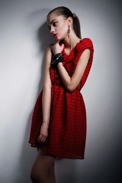 Молодая женщина в красном платье смотрит в сторону — стоковое фото