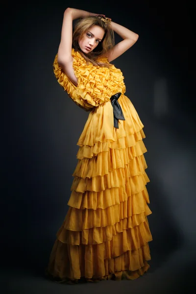 Eller başının arkasına sarı elbiseli güzel kadın — Stok fotoğraf